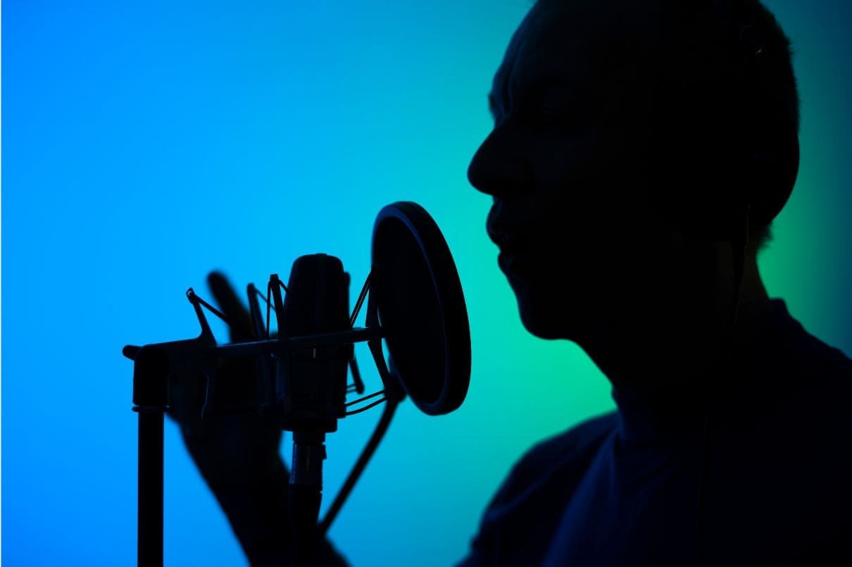A man singing into a microphone against a blue background